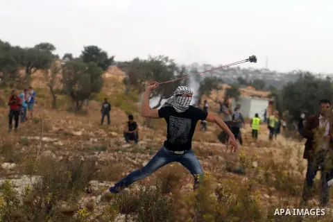 A Palestinian protester hurls stones towards Israeli security forces during clashes after a demonstration against Israel's separation barrier and in solidarity with Palestinian prisoners being held in Israeli jails, in t...