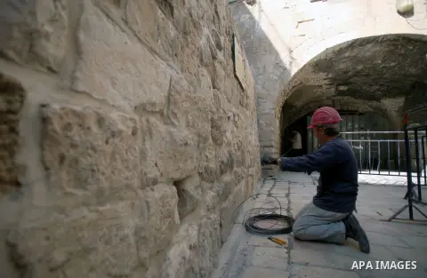 A laborer of Israeli Antiquities Authority works on a wall in entrance of Shihabi neighborhood next to the Al-Aqsa Mosque, in Jerusalem's Old City on November 11, 2013. Israeli Antiquities Authority intends to transform...