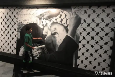 A Palestinian boy walks past a picture of late leader Yasser Arafat during the official commemorations of the 9th anniversary of his death, in the West Bank city of Ramallah, November 10, 2013. Arafat died Nov. 11, 2004...