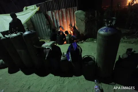 Palestinian men wait for the night to fill cooking gas canisters outside a filling station at Deir al-Balah in central Gaza Strip November 12, 2013. Palestinian officials said Israel allows limited quantity of cooking ga...