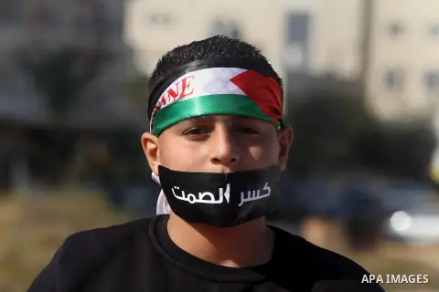 A Palestinian boy wears tape over his mouth during a demonstration in solidarity with Palestinian prisoners in Israeli jails, in the West Bank City of Ramallah, November 13, 2013. A human rights report said on Tuesday th...