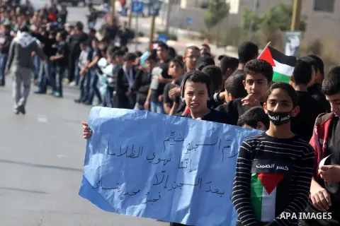 Palestinian protesters hold placards and flags during a demonstration in solidarity with Palestinian prisoners in Israeli jails, in the West Bank City of Ramallah, November 13, 2013. A human rights report said on Tuesday...
