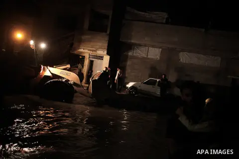 A Palestinian man carries his daughter as he walks in a flooded street with sewage in al-Sabra neighborhood, in Gaza City on November 13, 2013. The main pump of sewage water which serves thousands of citizens in a densel...