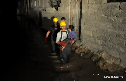 Palestinian workers carry children as they walk in a flooded street with sewage in al-Sabra neighborhood, in Gaza City on November 13, 2013. The main pump of sewage water which serves thousands of citizens in a densely p...
