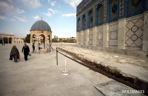 Palestinian women walk next to a ditch during a restoration work in front of the Dome of the Rock mosque at the al-Aqsa compound, in Jerusalem's old city on November 13, 2013. Restoration works started at al-Aqsa compoun...