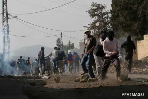 Palestinian protesters run seek for cover from tear gas fired by Israeli security forces during clashes following a protest against the expropriation of Palestinian land by Israel in the village of Kfar Qaddum, near the...