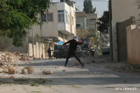 Palestinian protesters throw stone towards Israeli security forces during clashes following a protest against the expropriation of Palestinian land by Israel in the village of Kfar Qaddum, near the occupied West Bank cit...