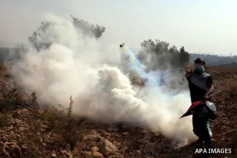 A Palestinian protestor hurls a tear gas canister back at Israeli troops during the weekly demonstration against Israel's separation barrier in the West Bank village of Bilin, near Ramallah, Friday, Nov. 15, 2013. . Phot...