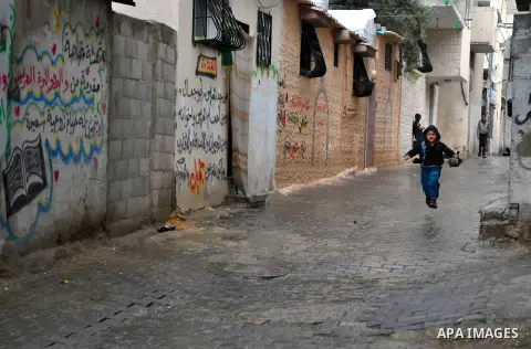 Palestinian children walk in a flooded street during a rainy day at al-Shati refugee camp, the third largest in the Palestinian Territories, in Gaza City on November 11, 2013. Photo by Mohammed Talatene