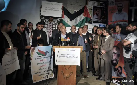 Palestinian journalists hold placards and candles during a protest in solidarity with the local al-Quds TV on the first anniversary of targeting their offices by Israeli warplanes, in Gaza City on November 18, 2013. The...