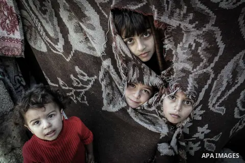 Palestinian children look through a curtain outside their tin shacks in Khan Younis refugee camp, in southern Gaza Strip, November 21, 2013. The UNRWA, which is facing a 36-million dollar deficit, halted 19 out of 20 con...