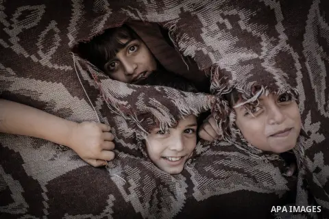 Palestinian children look through a curtain outside their tin shacks in Khan Younis refugee camp, in southern Gaza Strip, November 21, 2013. The UNRWA, which is facing a 36-million dollar deficit, halted 19 out of 20 con...