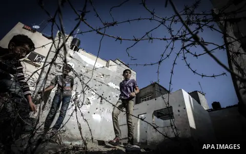 Palestinian children play outside their tin shacks in Khan Younis refugee camp, in southern Gaza Strip, November 21, 2013. The UNRWA, which is facing a 36-million dollar deficit, halted 19 out of 20 construction projects...
