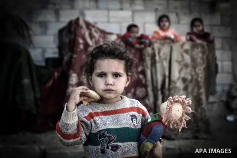 Palestinian children play outside their tin shacks in Khan Younis refugee camp, in southern Gaza Strip, November 21, 2013. The UNRWA, which is facing a 36-million dollar deficit, halted 19 out of 20 construction projects...