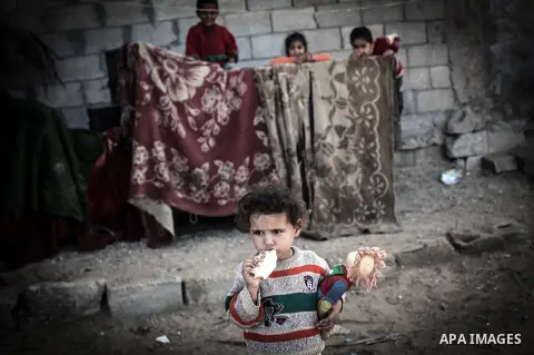 Palestinian children play outside their tin shacks in Khan Younis refugee camp, in southern Gaza Strip, November 21, 2013. The UNRWA, which is facing a 36-million dollar deficit, halted 19 out of 20 construction projects...