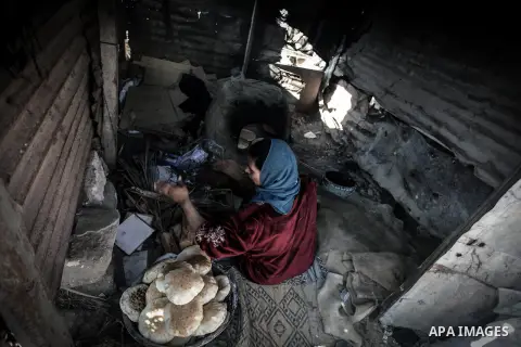 A Palestinian woman bakes bread on firewood, at her tin shack in Khan Younis refugee camp, in southern Gaza Strip, November 21, 2013. The UNRWA, which is facing a 36-million dollar deficit, halted 19 out of 20 constructi...