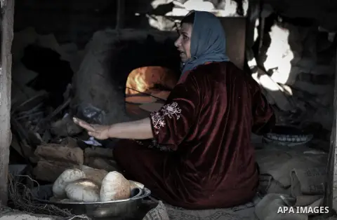A Palestinian woman bakes bread on firewood, at her tin shack in Khan Younis refugee camp, in southern Gaza Strip, November 21, 2013. The UNRWA, which is facing a 36-million dollar deficit, halted 19 out of 20 constructi...