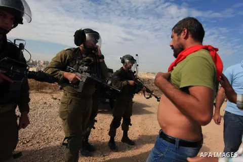 A Palestinian man argues with Israeli border policemen during the weekly demonstration against Israel's separation barrier in the West Bank village of Bilin, near Ramallah, Friday, Nov. 22, 2013. Photo by Issam Rimawi