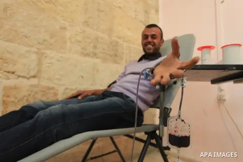 Palestinian youth donates blood during the launch of campaign " the good gathered" in the West Bank city of Ramallah on Nov. 23, 2013. Photo by Issam Rimawi