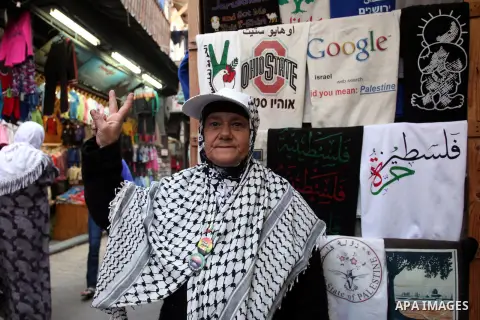 A Palestinian old woman flashes a victory sign at a market in Jerusalem's Old City on November 26, 2013. Photo by Saeed Qaq