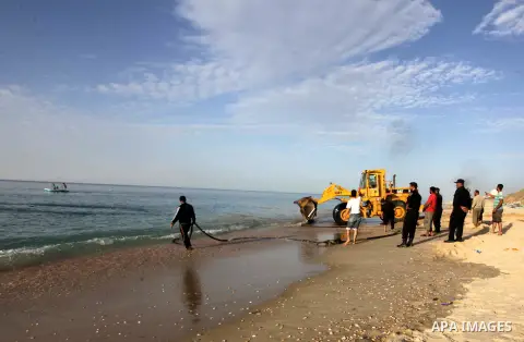 Palestinians watch as workers use a bulldozer to tow an old cannon which was found in the Mediterranean Sea off the coast of Deir al-Balah in central Gaza Strip, Tuesday, Nov. 26, 2013. Gaza Strip residents last month in...