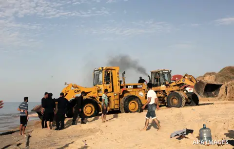 Palestinians watch as workers use a bulldozer to carry an old cannon which was found in the Mediterranean Sea off the coast of Deir al-Balah in central Gaza Strip, Tuesday, Nov. 26, 2013. Gaza Strip residents last month...