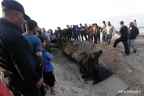 Palestinians watch as workers use a bulldozer to carry an old cannon which was found in the Mediterranean Sea off the coast of Deir al-Balah in central Gaza Strip, Tuesday, Nov. 26, 2013. Gaza Strip residents last month...