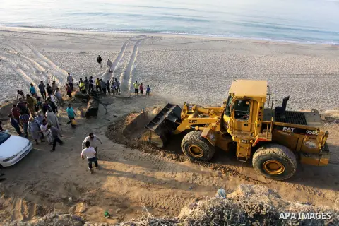 Palestinians watch as workers use a bulldozer to carry an old cannon which was found in the Mediterranean Sea off the coast of Deir al-Balah in central Gaza Strip, Tuesday, Nov. 26, 2013. Gaza Strip residents last month...