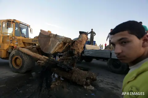 Palestinians watch as workers use a bulldozer to carry an old cannon which was found in the Mediterranean Sea off the coast of Deir al-Balah in central Gaza Strip, Tuesday, Nov. 26, 2013. Gaza Strip residents last month...