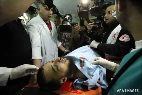 Palestinians stand beside the body of a militant at a hospital in Yatta village of the West Bank city of Hebron on Nov. 27, 2013. Israeli forces killed three Palestinian militants Tuesday in clashes near the West Bank ci...