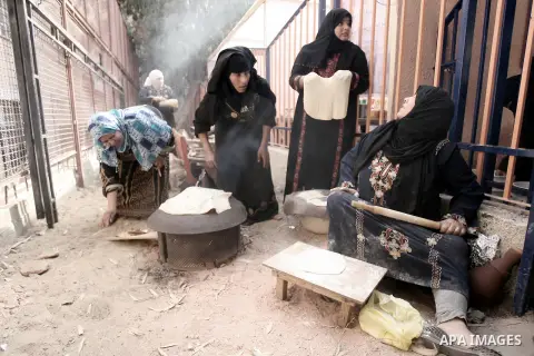 Palestinian women bake traditional bread on firewood at the Palestinian Heritage Exhibition in the town of Khan Yunis, in the southern Gaza Strip, November 27, 2013. Palestinians attend the Heritage Exhibition every year...