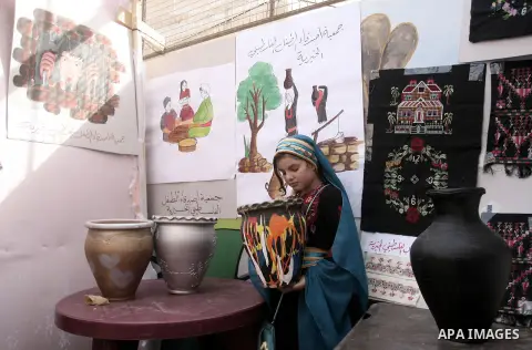 A Palestinian girl takes part in the Palestinian Heritage Exhibition in the town of Khan Yunis, in the southern Gaza Strip, November 27, 2013. Palestinians attend the Heritage Exhibition every year to practice heritage r...