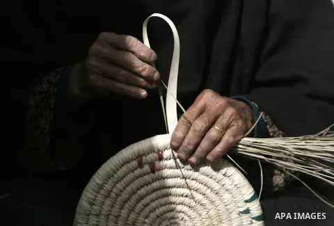 A Palestinian woman makes a traditional straw dish at the Palestinian Heritage Exhibition in the town of Khan Yunis, in the southern Gaza Strip, November 27, 2013. Palestinians attend the Heritage Exhibition every year t...