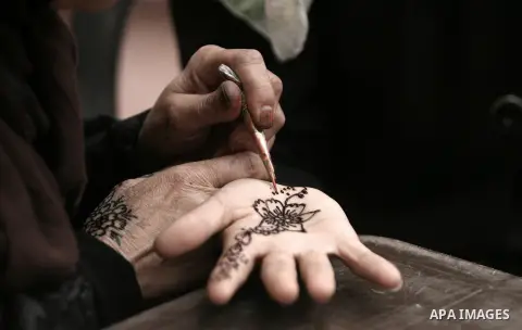 A Palestinian woman paints a traditional henna tattoo for a client at the Palestinian Heritage Exhibition in the town of Khan Yunis, in the southern Gaza Strip, November 27, 2013. Palestinians attend the Heritage Exhibit...