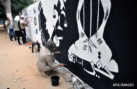 Palestinian youths draw a mural as part of a popular campaign to demand the inheritance rights of women in Gaza City on November 27, 2013. Reports of human rights in Gaza Strip pointed out that about 90% of the women who...