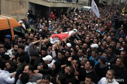 Palestinian mourners carry the body of Mahmud Waji Awad, a Palestinian man who died the previous day of his injuries after he was shot in a 2012 clash with Israeli troops, during his funeral in the West Bank's Qalandiya...