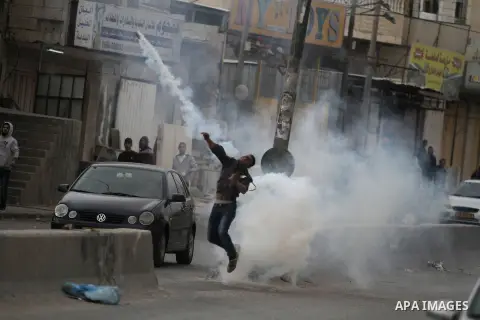A Palestinian protester throws back a tear gas canister fired by Israeli security forces during clashes following a demonstration against the killing of Mahmud Waji Awad, a Palestinian man who died the previous day of hi...