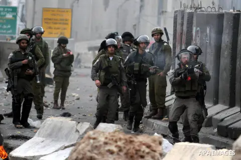 A member of Israeli security forces fires a tear gas canister towards Palestinian protesters during clashes following a demonstration against the killing of Mahmud Waji Awad, a Palestinian man who died the previous day o...