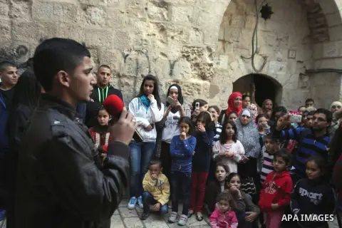 Palestinian children take part in an activities to encourage people of the area to stay in their homes Al-Qurma neighborhood of the Old City, on Nov. 30, 2013. Landslides began seven years ago due to the network of tunne...