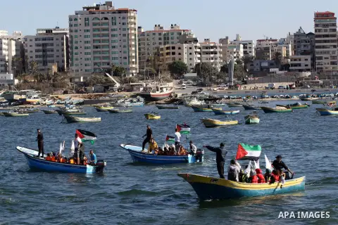 Palestinian children sit on boats before launching in water model boats, with their names and countries' names on sails, during a rally to protest against the Israeli siege of the Gaza Strip on November 30, 2013 at Gaza...