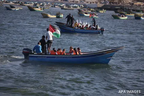 Palestinian children sit on boats before launching in water model boats, with their names and countries' names on sails, during a rally to protest against the Israeli siege of the Gaza Strip on November 30, 2013 at Gaza...