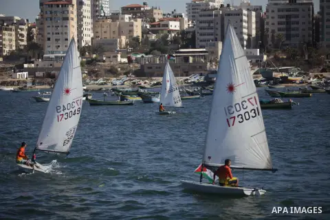 Palestinian children sit on boats before launching in water model boats, with their names and countries' names on sails, during a rally to protest against the Israeli siege of the Gaza Strip on November 30, 2013 at Gaza...