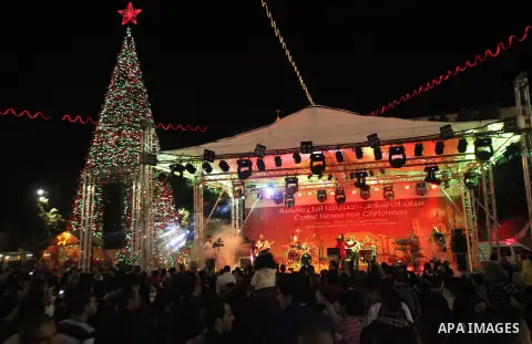 Palestinians celebrate the lighting of the Christmas tree in Manger Square, outside the Church of the Nativity, in the West Bank town of Bethlehem, believed to be the birthplace of Jesus Christ as preparations for Christ...