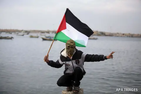 Palestinians pose hold Palestinian national flags before a convoy of boats is launched at the initiative of the "Intifada Youth Coalition" (IYC) to break the naval blockade of Gaza as a protest against the Israeli siege...