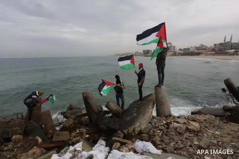 Palestinians pose hold Palestinian national flags before a convoy of boats is launched at the initiative of the "Intifada Youth Coalition" (IYC) to break the naval blockade of Gaza as a protest against the Israeli siege...