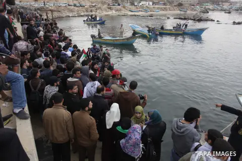 Palestinians look at boats leaving as a convoy is launched at the initiative of the "Intifada Youth Coalition" (IYC) to break the naval blockade of Gaza as a protest against the Israeli siege on December 2, 2013 at the p...