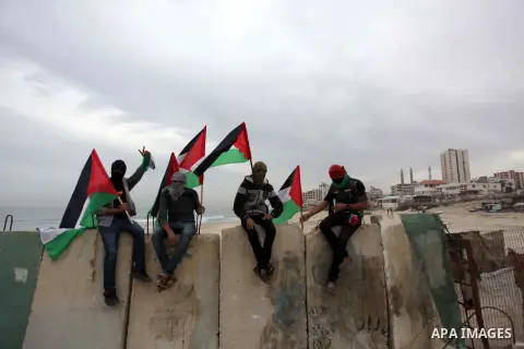 Palestinians pose hold Palestinian national flags before a convoy of boats is launched at the initiative of the "Intifada Youth Coalition" (IYC) to break the naval blockade of Gaza as a protest against the Israeli siege...