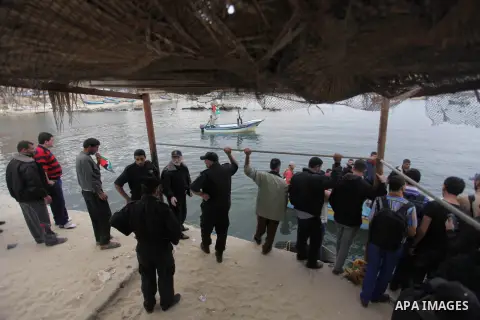 Palestinians look at boats leaving as a convoy is launched at the initiative of the "Intifada Youth Coalition" (IYC) to break the naval blockade of Gaza as a protest against the Israeli siege on December 2, 2013 at the p...