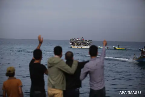 Palestinians wave to a convoy of boats leaving the port of Gaza at the initiative of the "Intifada Youth Coalition" (IYC) to break the naval blockade of Gaza as a protest against the Israeli siege on December 2, 2013 in...