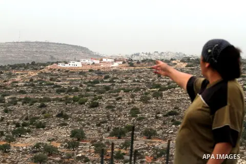 A Palestinian woman from the village of al-Mazraa al-Kubliyeh looks a bungalows in the distance built by Israeli settlers at an outpost constructed on seized land from the Palestinian village, near the West Bank city of...